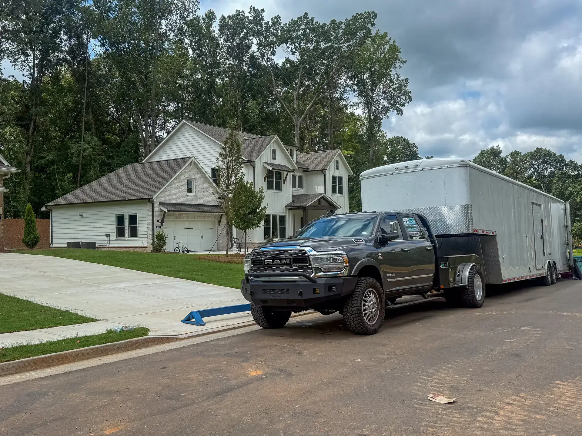 First Class Relocation moving truck and enclosed trailer outside a home